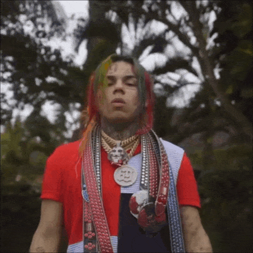 a man with colorful hair is wearing a red shirt and a scarf around his neck ..