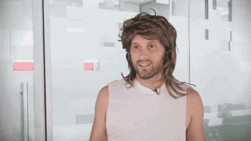a man wearing a wig and a white tank top is pointing up