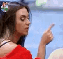 a woman in a red off the shoulder top is pointing her finger at something .