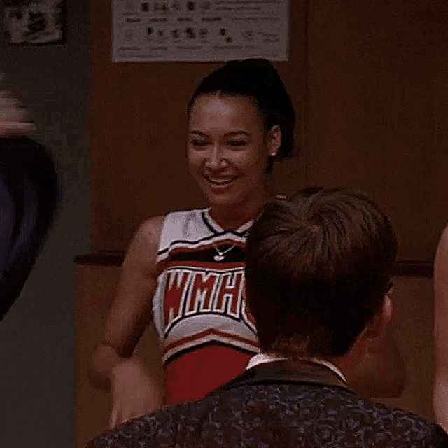 a woman in a cheerleader outfit is giving a high five to a man .