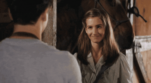 a man and a woman are standing in front of a horse in a stable