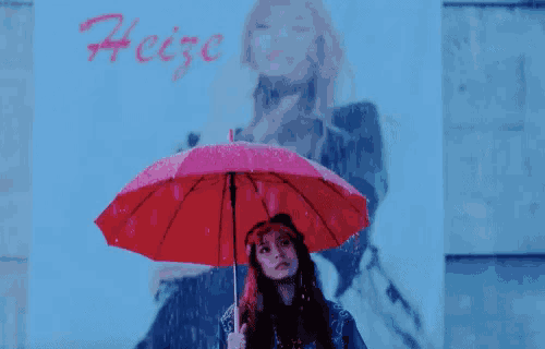 a woman is holding a red umbrella in front of a poster of a woman .