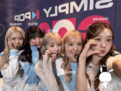 a group of girls posing in front of a wall that says yjqmic