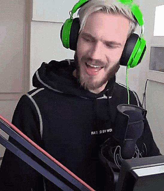 a man wearing green headphones and a black hoodie that says radio station on the front