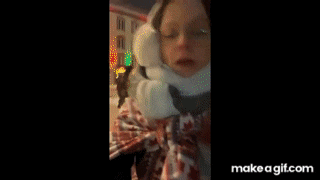 a woman wearing ear muffs and a scarf is laying on a bed in front of a christmas tree .