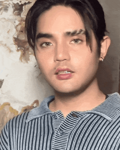 a young man with a striped shirt on looks at the camera