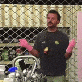 a man wearing pink rubber gloves is standing in front of a grill