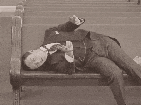 a man in a suit is laying down on a wooden bench