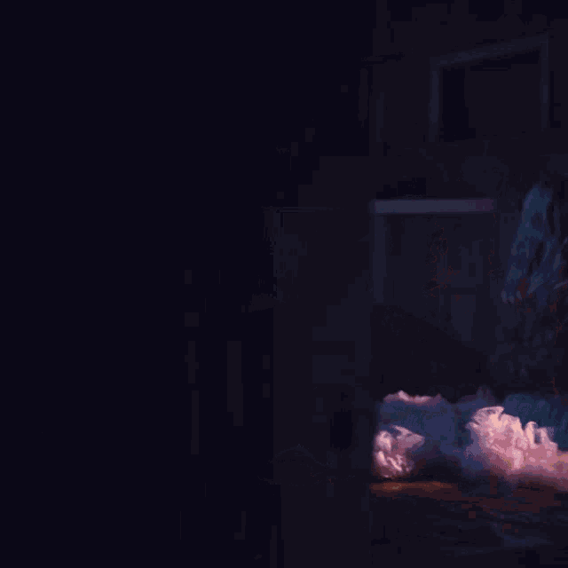 a woman in a pink dress is sitting on a bed in the dark