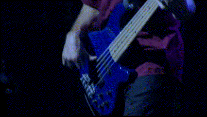 a person playing a blue electric guitar in a dark room