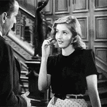 a man and a woman are standing next to each other in front of a staircase in a black and white photo .
