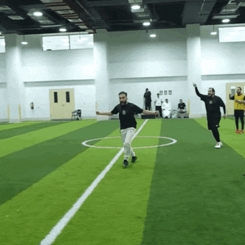 a group of men are playing soccer in a large indoor arena