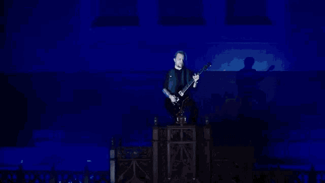 a man is sitting on a throne playing a guitar on a stage in a dark room .