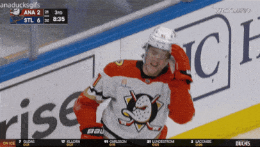 a hockey player stands in front of a victory sign