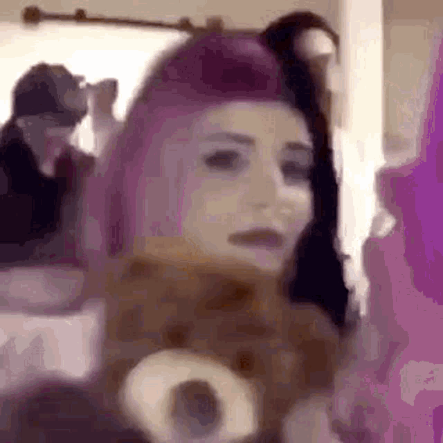 a woman with pink hair is holding a teddy bear and taking a picture of herself .