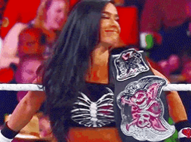 a woman is wearing a skeleton top and holding a wrestling championship belt .