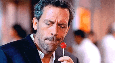 a man in a suit is eating a lollipop with his mouth open .
