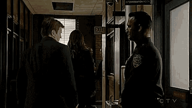 two police officers are standing next to each other in a hallway .