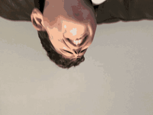 a man 's head is upside down and smiling at the camera