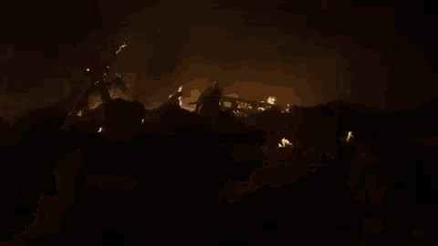 a man in armor is standing in front of a burning city .
