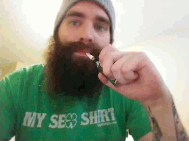 a bearded man wearing a green shirt that says my sex shirt