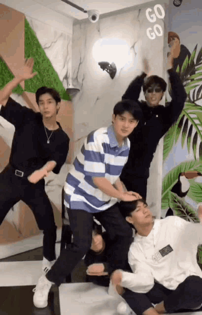 a group of young men are posing for a picture in front of a wall with the words go go on it