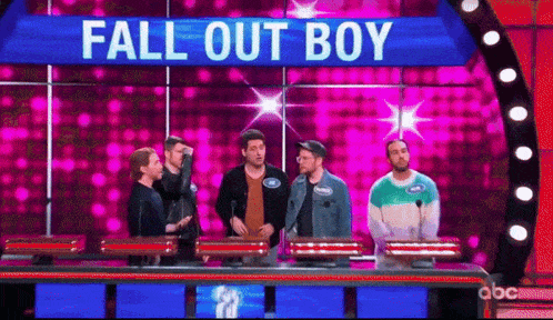 a group of men are standing on a stage with a sign that says `` fall out boy '' .
