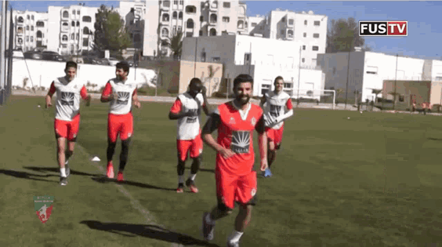 a group of soccer players are running on a field with the words fustv on the bottom