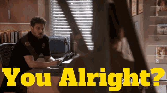 a man sitting at a desk with the words " you alright " on the top
