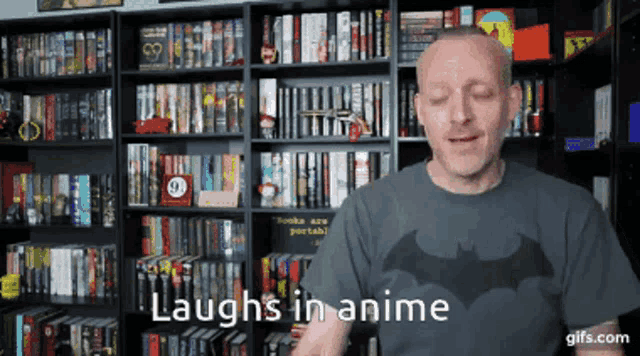 a man wearing a batman shirt is laughing in front of a bookshelf