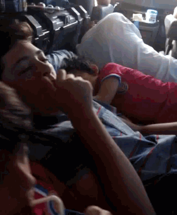 a boy in a red shirt is sleeping on a bed