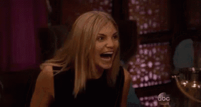 a woman is laughing with her mouth open while sitting in a chair .