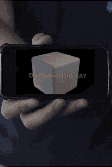 a person holding a cell phone with a picture of a cube on the screen