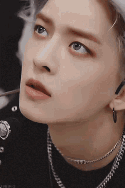 a close up of a person 's face with a necklace around his neck
