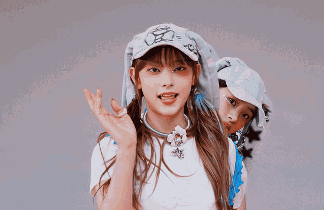 a girl wearing a hat that says ' i love you ' on it stands next to another girl