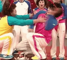a group of people are standing around a person in a pink shirt