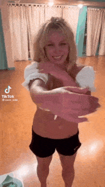 britney spears is standing in a room with her arms outstretched and smiling .