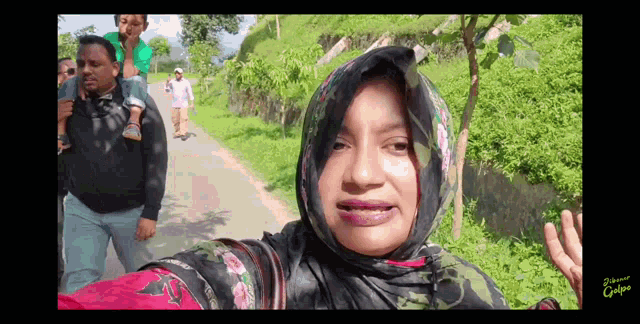 a woman in a hijab is taking a selfie with a man carrying a child