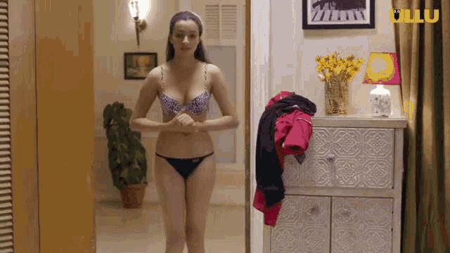 a woman in a bra and panties is standing in a room .