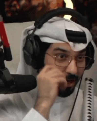 a man wearing headphones and glasses is talking into a microphone