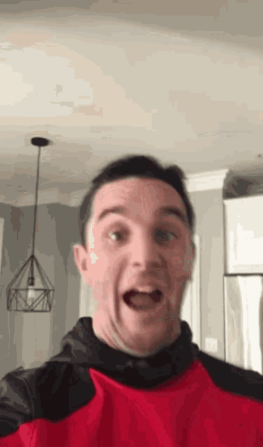 a man in a red and black shirt is making a surprised face