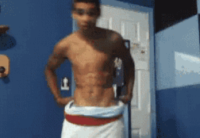 a shirtless man in a white towel is standing in front of a blue wall