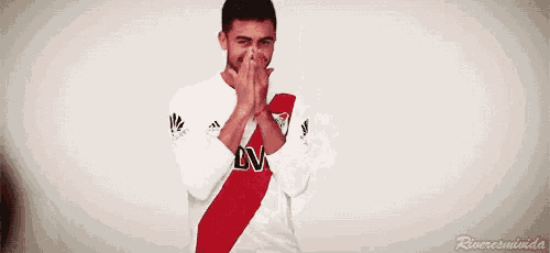 a man wearing a white shirt with a red stripe on the sleeve is clapping his hands .