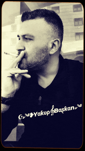 a man smoking a cigarette with a shirt that says yakup başkan