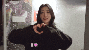 a woman is making a heart shape with her hands and says i love you
