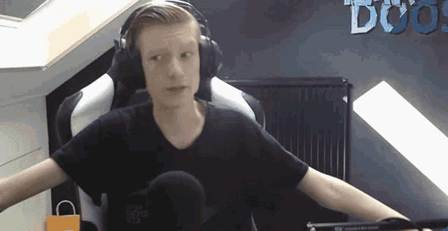 a boy wearing headphones is sitting in front of a sign that says doo
