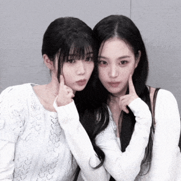 two girls are posing for a picture and one of them is pointing at her face