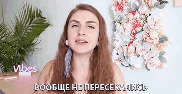 a woman is standing in front of a wall of flowers with vibes written on it