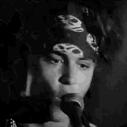 a black and white photo of a man singing into a microphone .