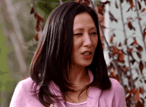 a woman in a pink sweater is making a face